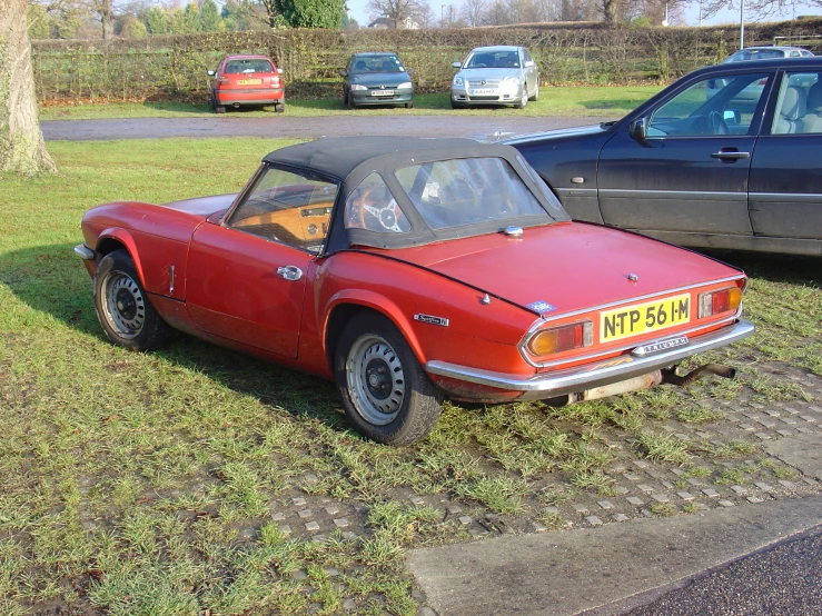 a car parked in the grass next to other cars