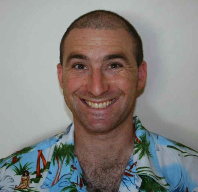 a man smiling for a po with palm trees on the shirt