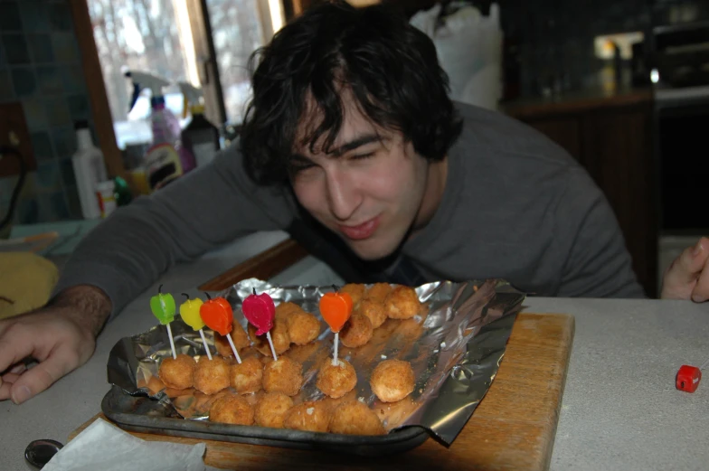 a man staring at some little candies on top of cake