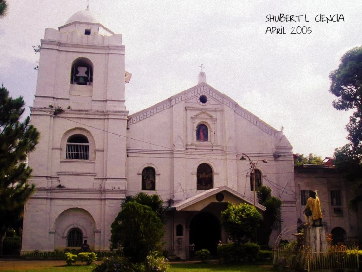 a church with white trim surrounded by shrubbery and trees