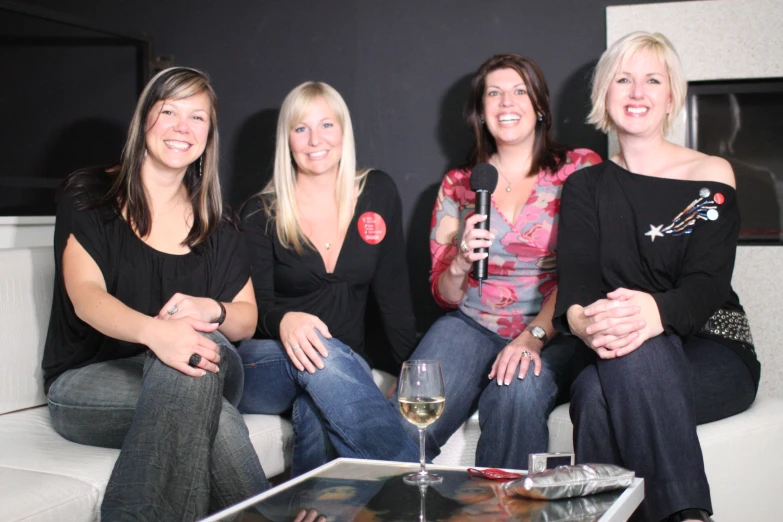 three woman are sitting together and holding a microphone