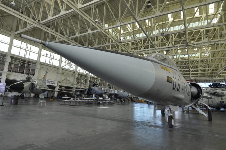 a military jet in the middle of an airport hanger