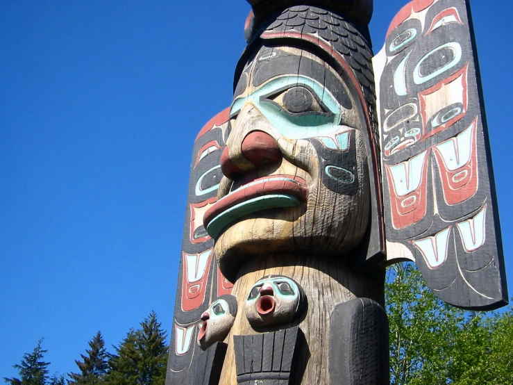 a wooden carving of a bird with three face heads