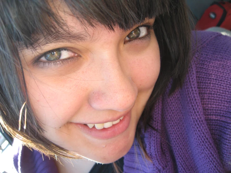 a woman wearing a purple sweater is smiling for the camera