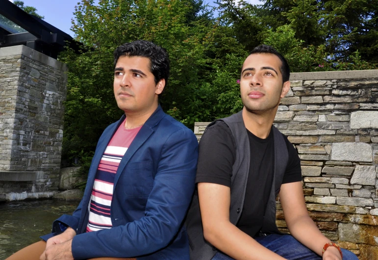 two men are sitting on the edge of a ledge