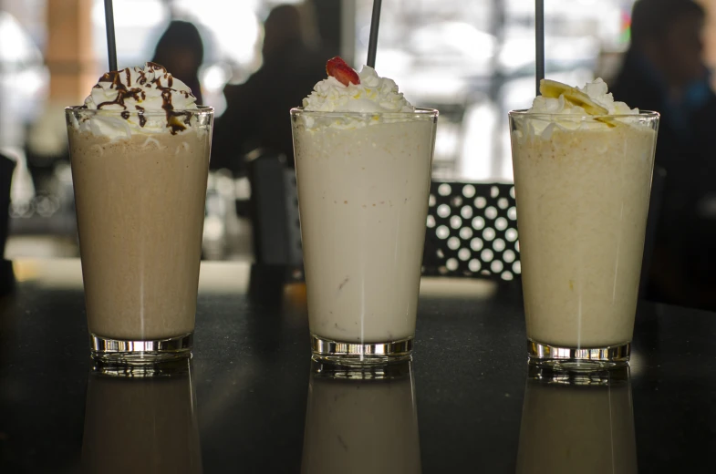 three drinks sitting on top of a table with ice cream in them