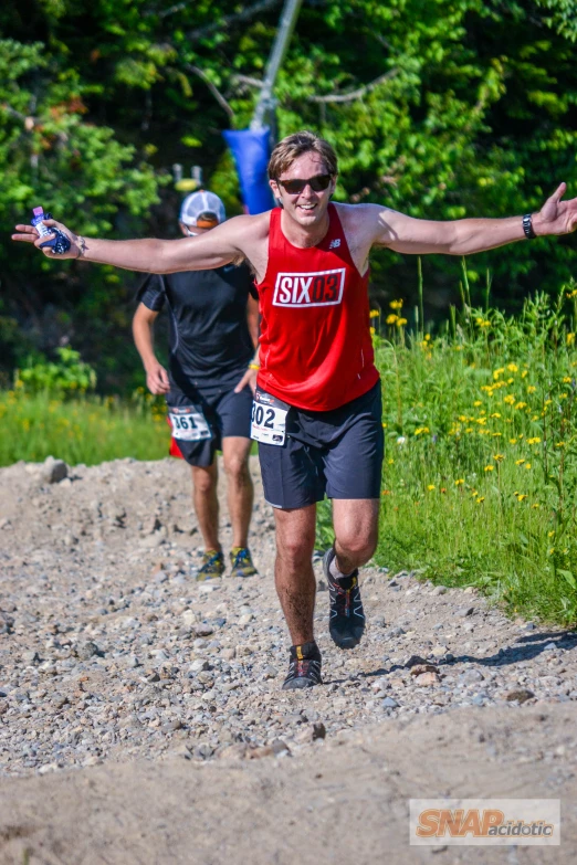 two men are running down a trail in red and black