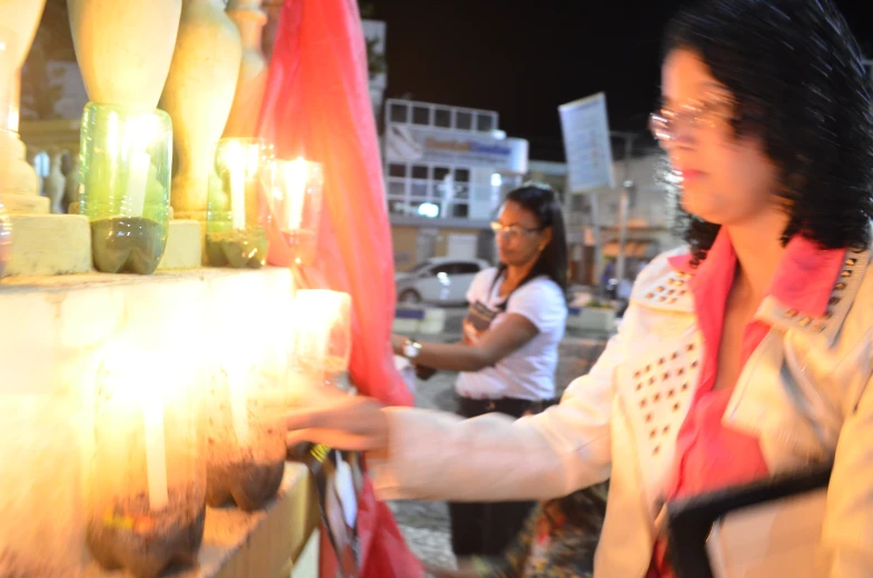 women looking through glass candles on display in public area