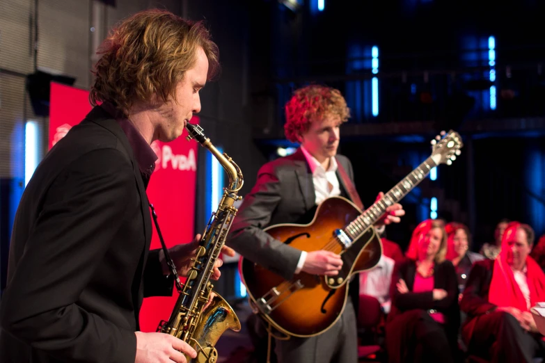 the man plays a saxophone while other musicians look on