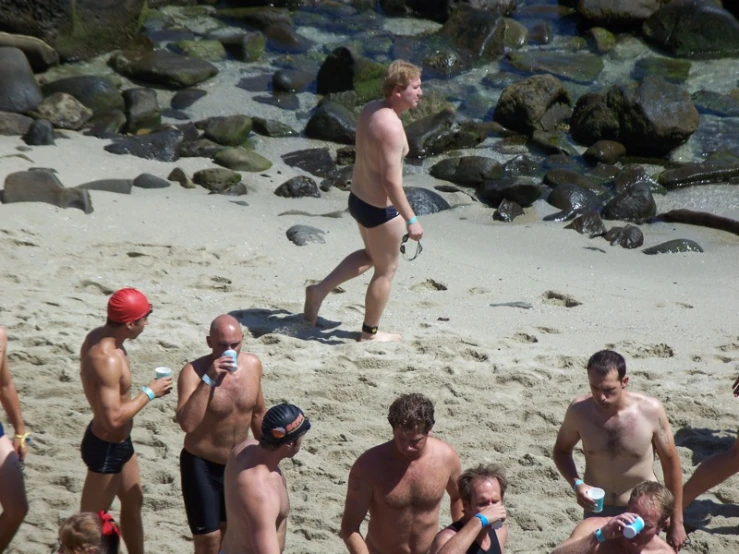 a bunch of men standing and lying on a beach