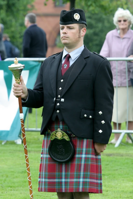 the man in a kilt is holding a ss cup