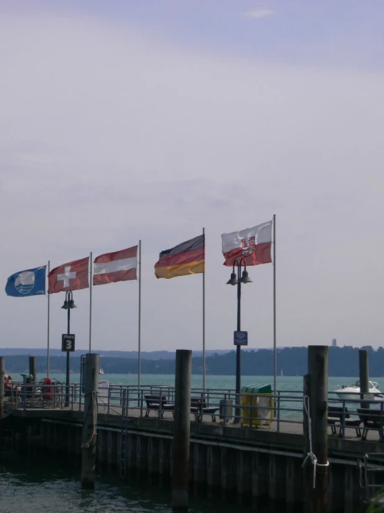 several flags are flying near a boat dock