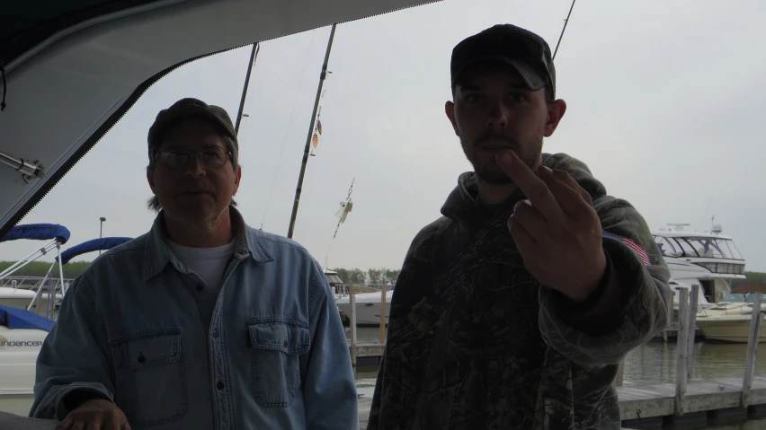 two men standing in front of some boats on the water