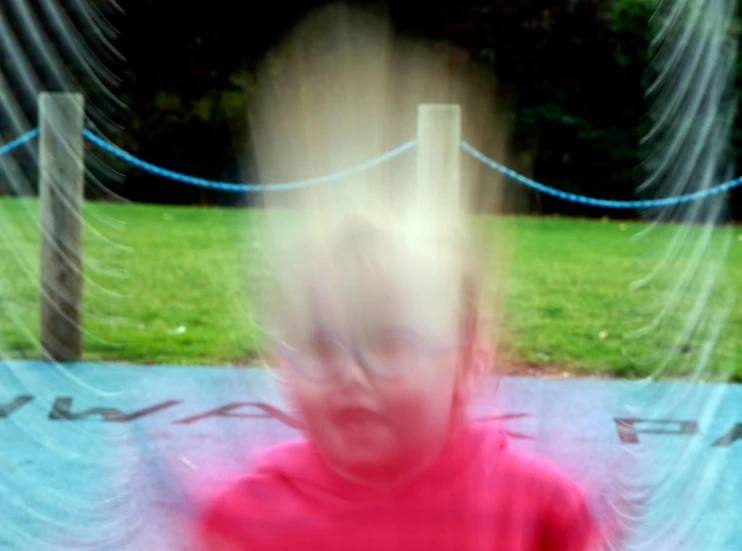 blurry image of young person with red shirt sitting on park bench