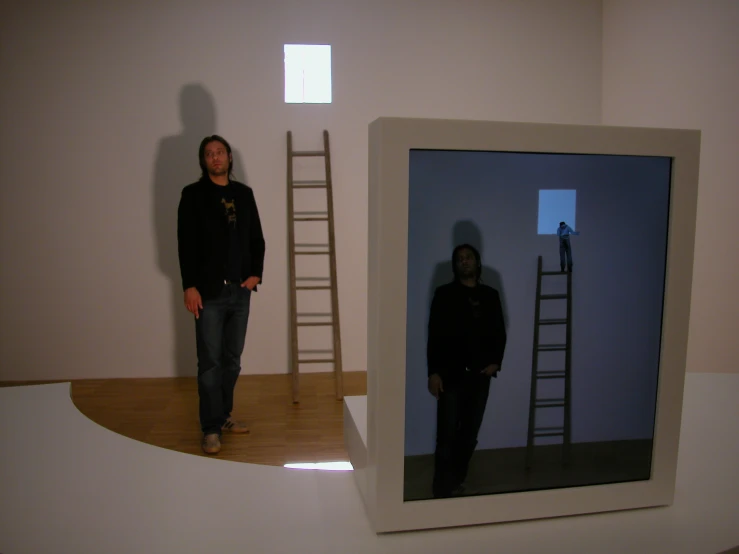 a man standing next to a ladder in front of a mirror