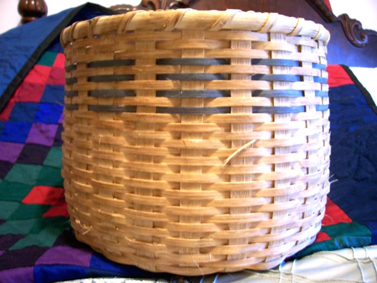 a woven basket on the bed with blue, green, purple and red blanket