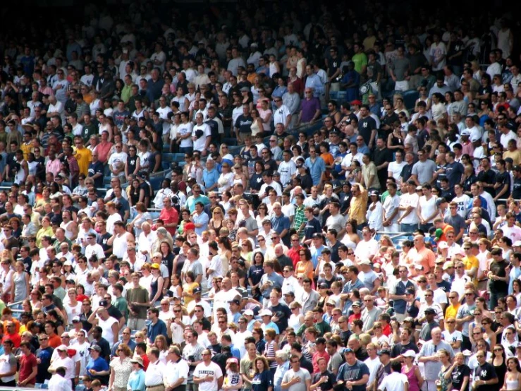 a crowd of people sitting in the stands at a tennis match