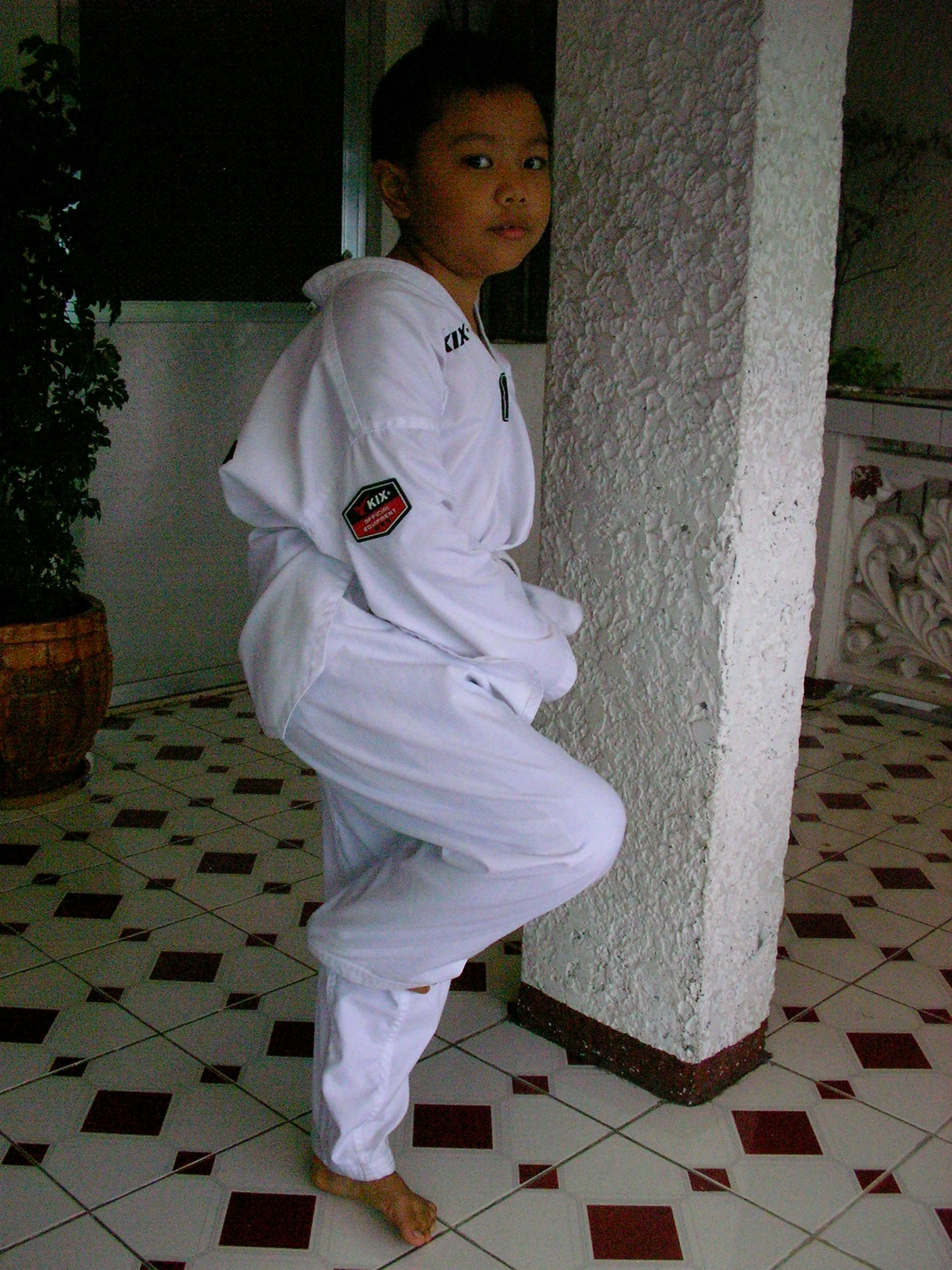 a girl wearing white clothes poses by a pillar