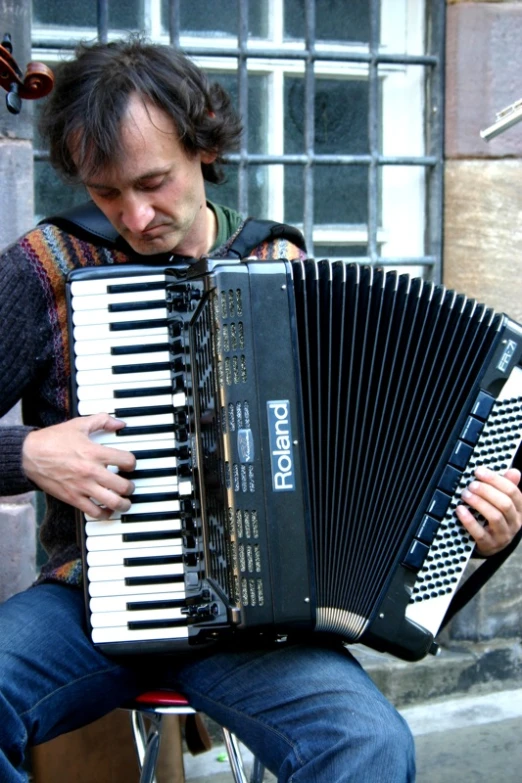 a man holding an accord piano while sitting on a chair