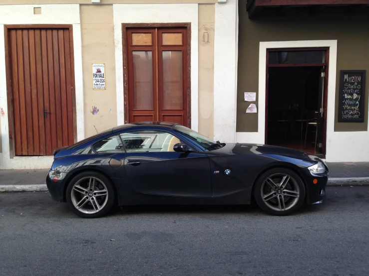 a dark colored sports car is parked in front of an apartment building