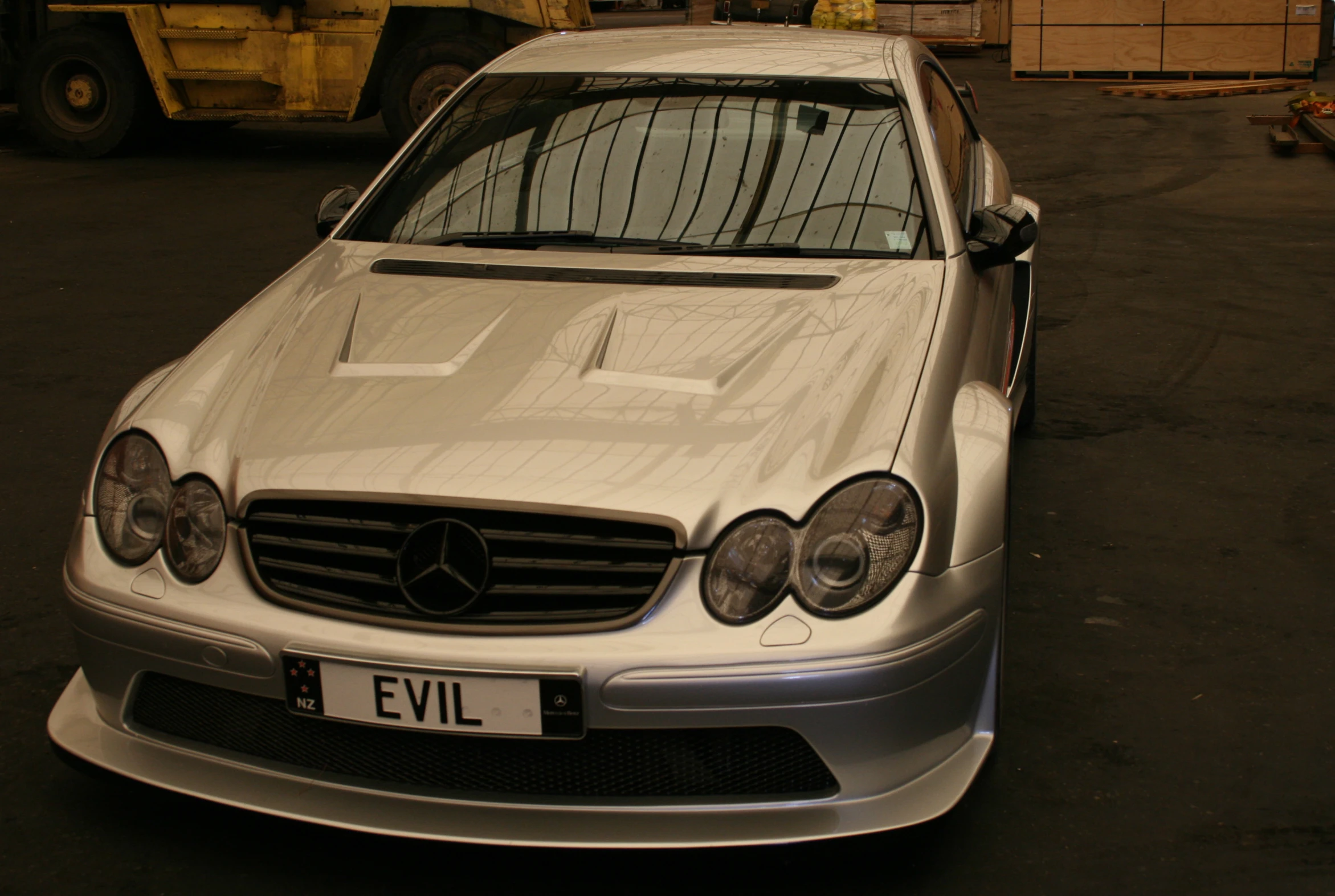 a silver car parked near the road near a truck