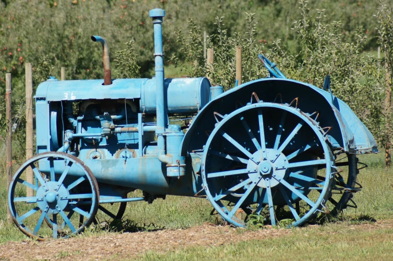 an old blue tractor is parked on the side of the road