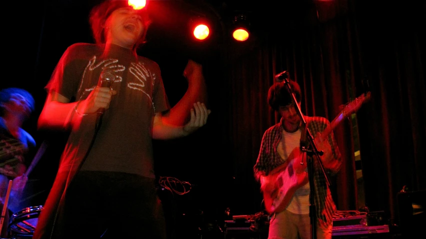 two men are singing and playing a guitar at night