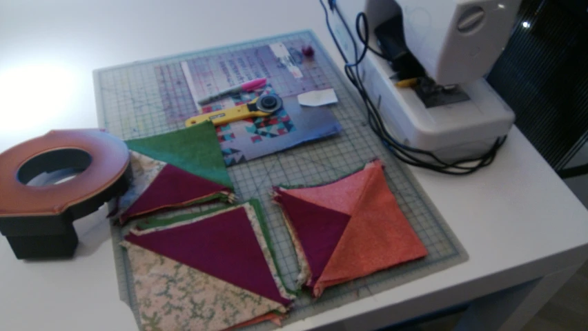 quilts sitting on top of a table near a sewing machine