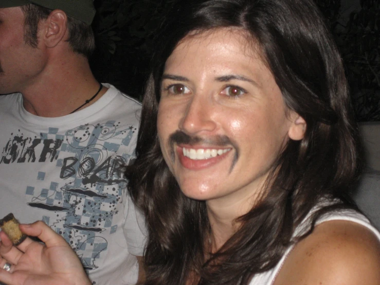 a smiling woman holds a piece of food