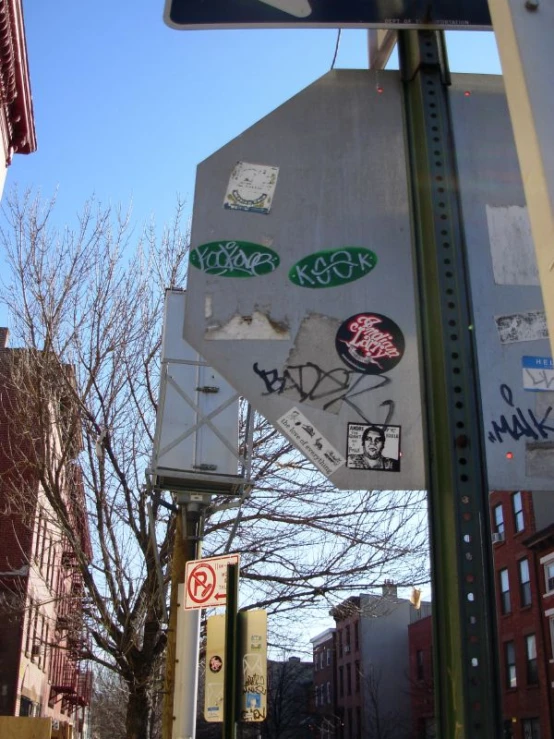 a traffic sign covered in stickers on the side of the road