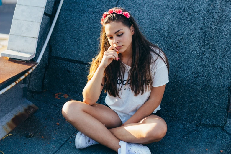 a woman in white sitting on the sidewalk