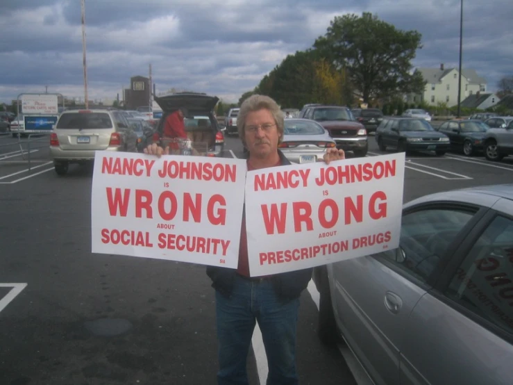 two people holding up signs on the side of the road