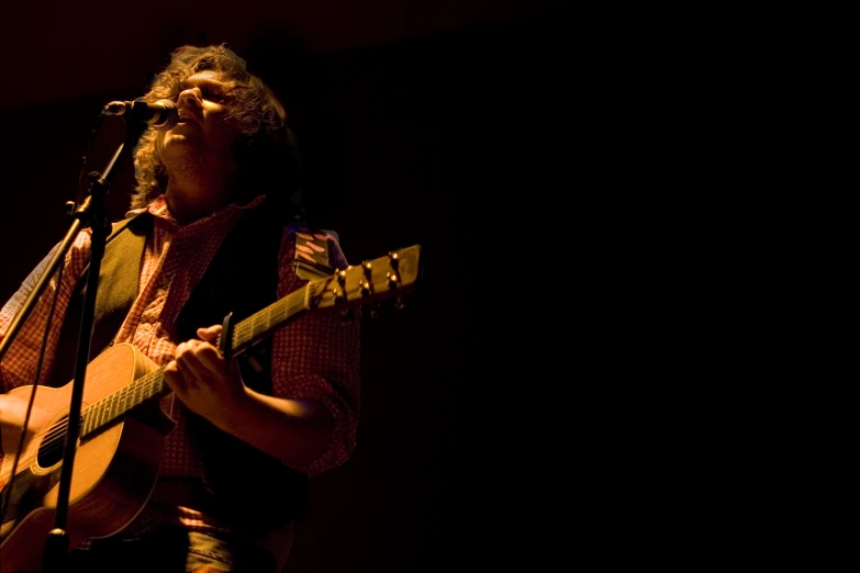 a man singing on a mic with a guitar