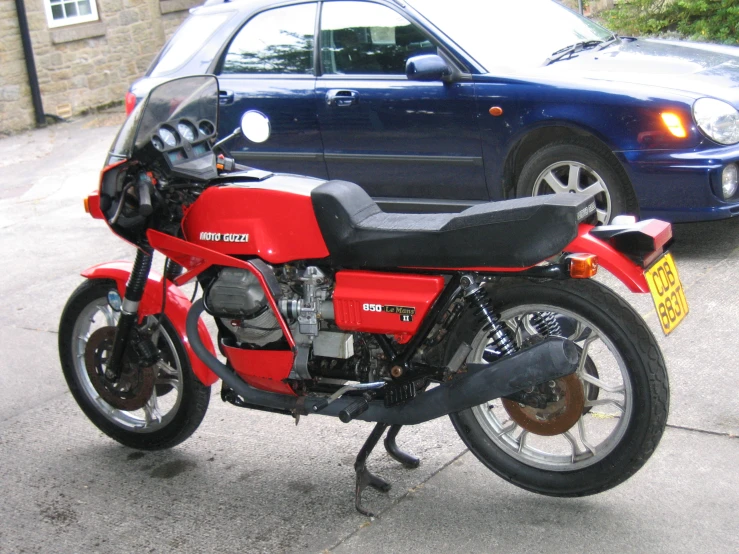 a red motorcycle parked next to a blue car