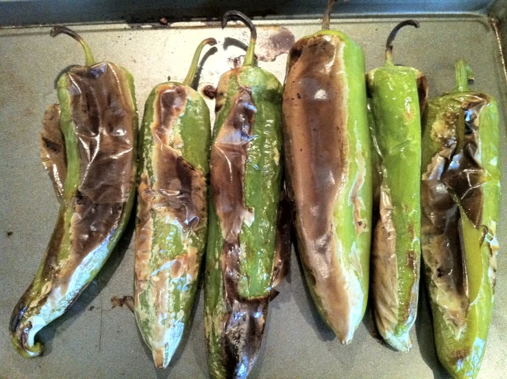 five green peppers sitting on a counter top