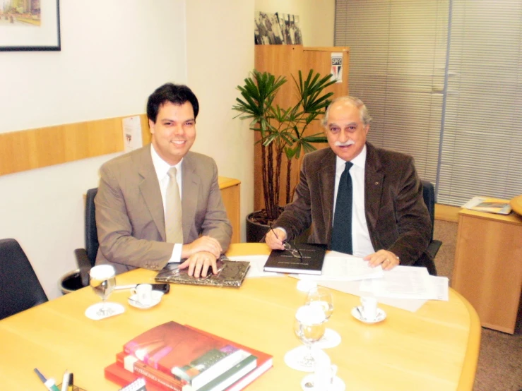 two men sitting in front of a laptop at a desk