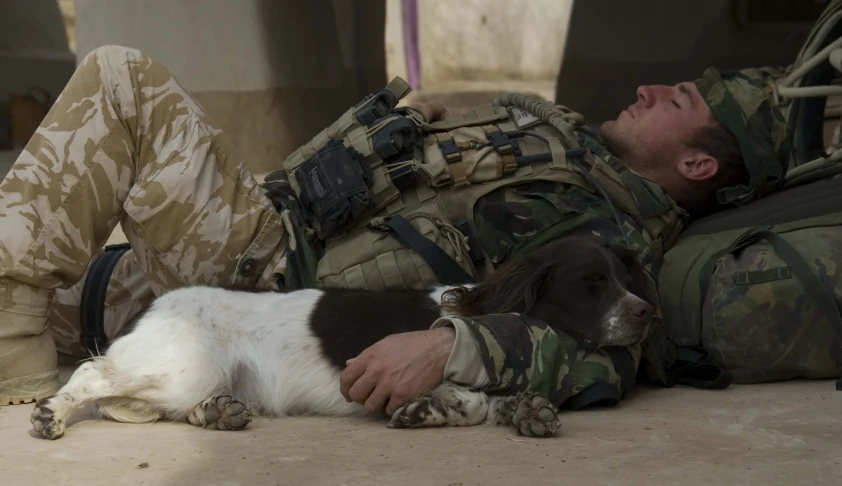 a soldier lays down next to his dog