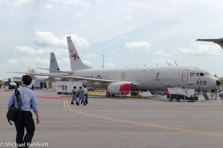 an airplane sitting at the airport near some people