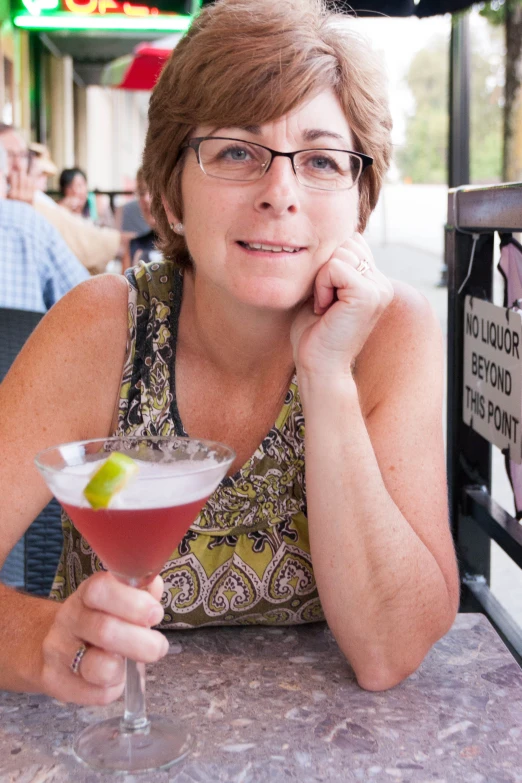 a lady that is sitting at a table with a drink