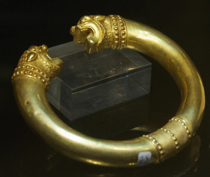 an old metal gold plated celet on a display case