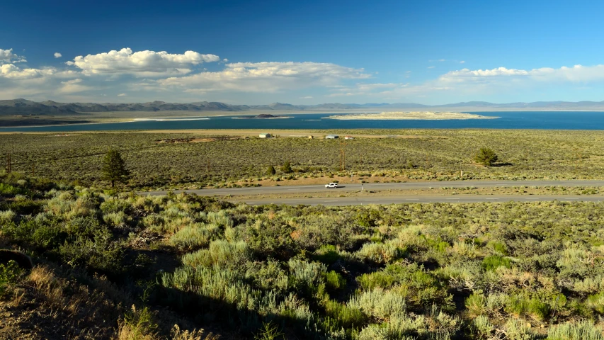 a wide open land with water and clouds in the distance