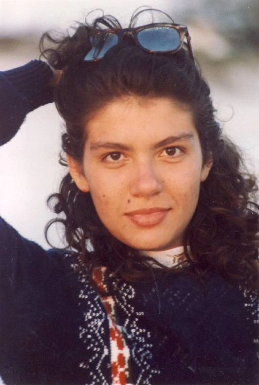 a young lady is standing wearing sunglasses and looking at the camera