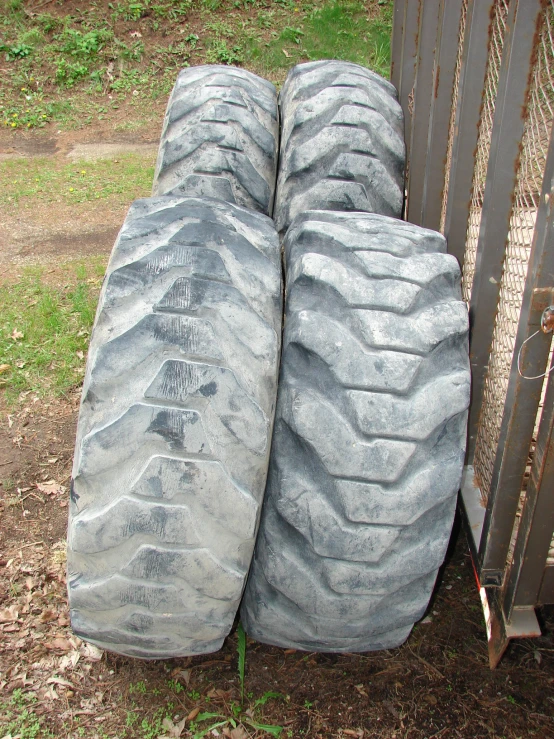 two big tires are in the dirt by the fence