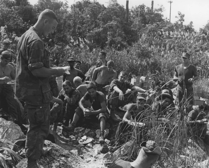 several soldiers are standing on the side of the road and several men are kneeling