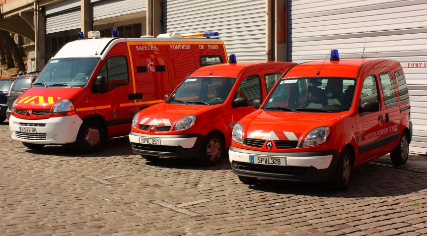 three vans are parked side by side on the cobblestone street