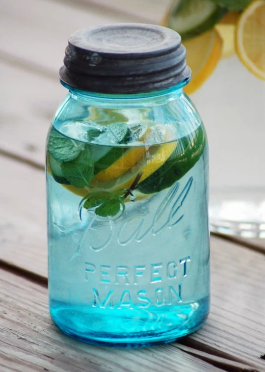 a glass jar is filled with water and lemon slices