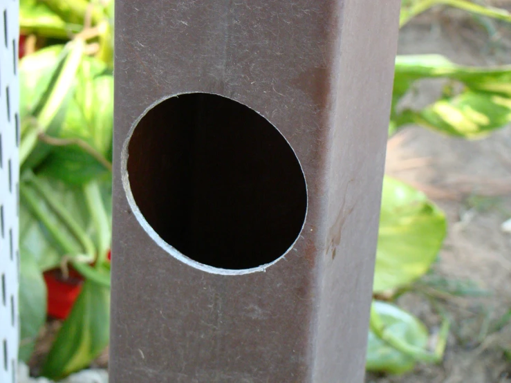 a small brown bird house sits next to a bush