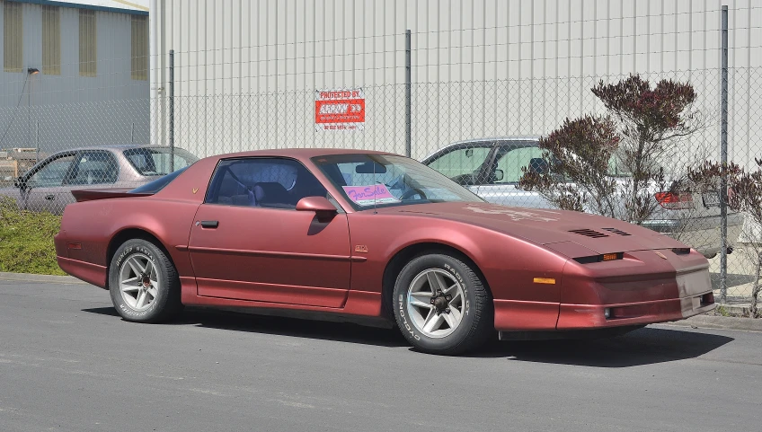 the red sports car is parked in front of the fence