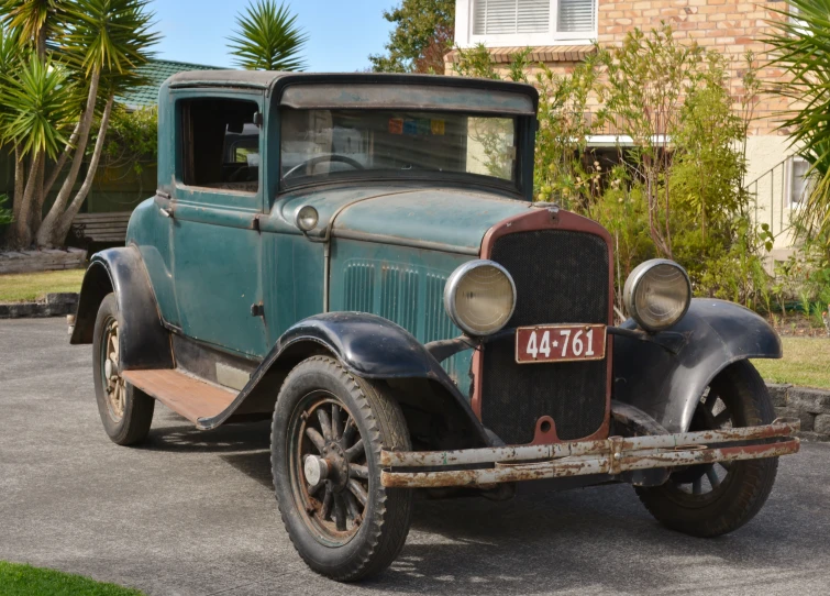 an old car in the driveway of a house