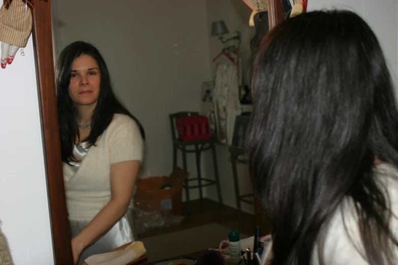 a woman with long hair brushing her hair in front of a mirror
